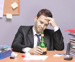 Man drinking alcohol while working
