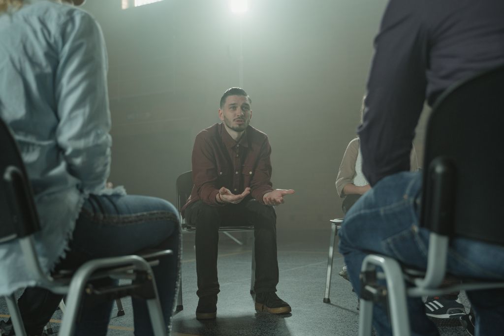 A man talking to a group in a rehab therapy session | Which Rehab