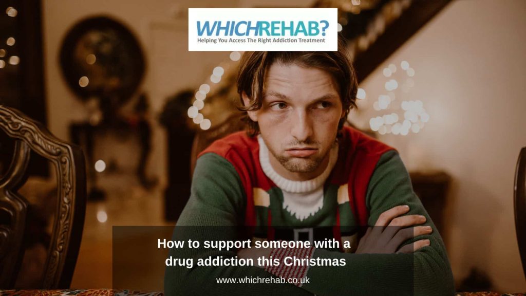 A man sat at a Christmas dinner table wearing a festive jumper looking sullen, with the Which Rehab logo above and the blog title - How to support someone with a drug addiction this Christmas below - Which Rehab