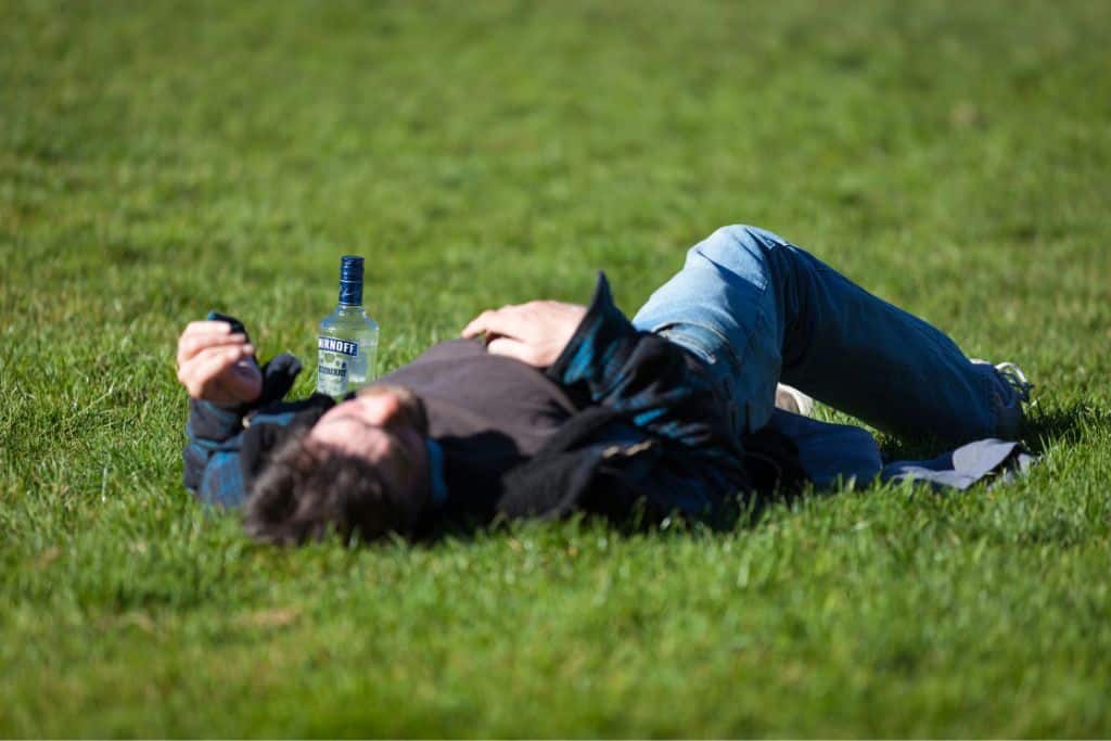 Man lying in grass struggling with alcoholism -Which Rehab?