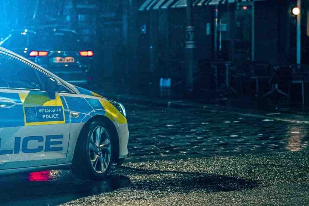 A police car on a raining London street at night - Which Rehab