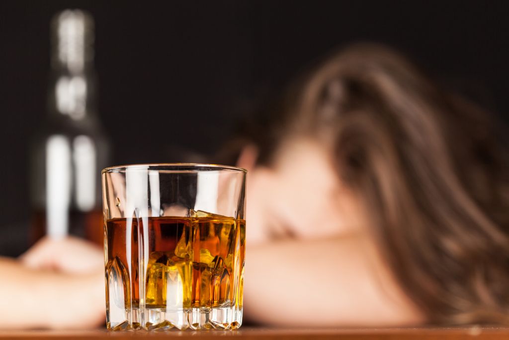 A woman slumped over a glass of whisky - the 4 treatments of alcoholism - Which Rehab