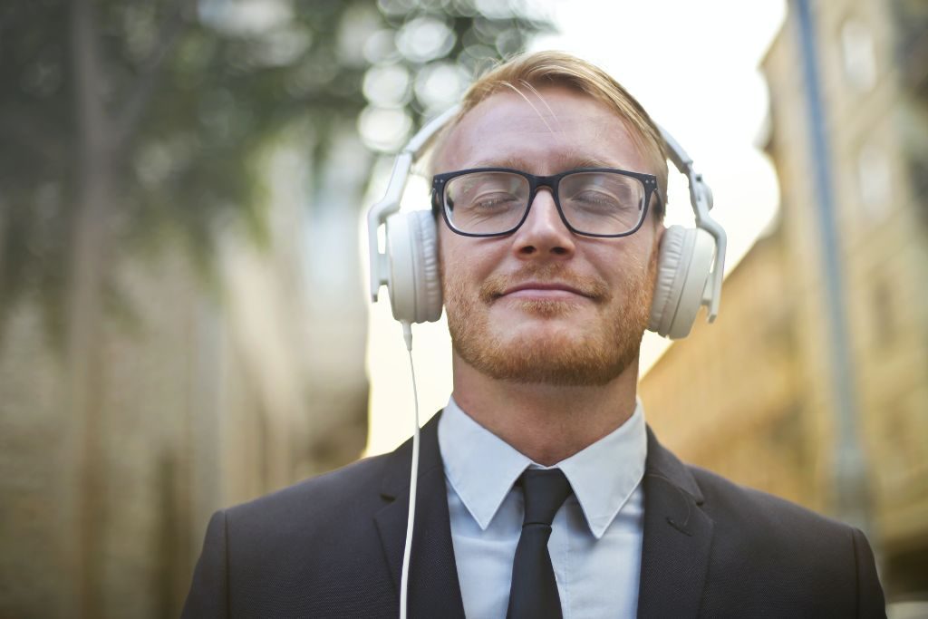 Man with closed wyes smiling with headphones on - Which Rehab
