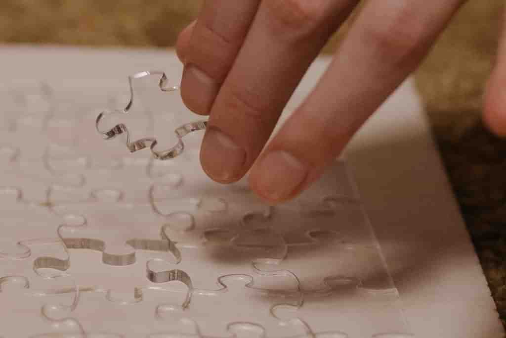 A person placing a transparent jigsaw piece in a puzzle - REBT Blog - Which Rehab